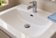 Dettaglio di lavabo in ceramica con tappo cromato, apertura del troppopieno e panno per la pulizia sul bordo